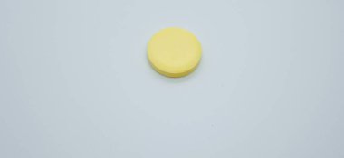 Beyaz arka planda izole edilmiş tek sarı renkli C vitamini hapı. C vitamini antioksidan içerir ve soğuk algınlığını ve virüsü korur. İlaç, uyuşturucu ve tıbbi konsept.