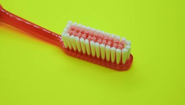 Diş fırçasının başı, sarı arka planda izole edilmiş. Diş fırçasının kılları, yakın çekim..
