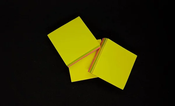 Stacked yellow note papers, isolated on the mini black studio.
