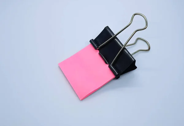 Pink note paper with black binder clip. Binder clip and stack of pink note paper.