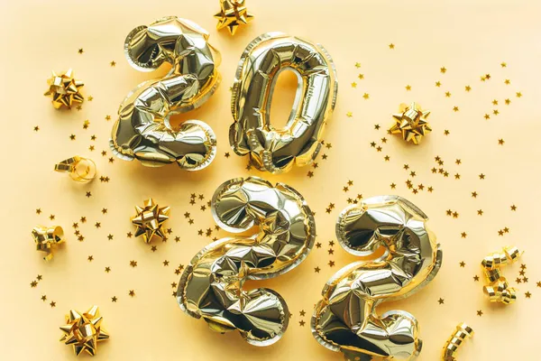Globos hechos de lámina de oro con los números 2022 sobre un fondo de oro con lentejuelas de oro. Celebrando la Navidad, Año Nuevo y el concepto de vacaciones. Fotos De Stock