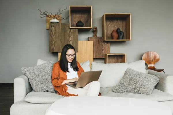 Una hermosa mujer joven europea usando un ordenador portátil para el trabajo remoto desde casa. Una mujer inteligente trabaja remotamente — Foto de Stock