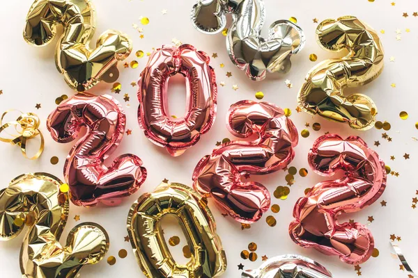 Multicolored Balloons made of foil in the form of numbers 2022 with confetti on a pink background.Celebrating Christmas, New Year and festive concept. — Stock Photo, Image