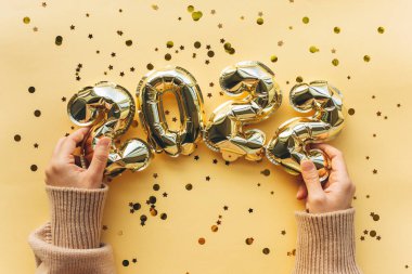 Kız, 2022 'de şişme balonları yeni yıl figürleri şeklinde tutuyor. Yılbaşı ve Noel konseptinin şenlikli arka planı.