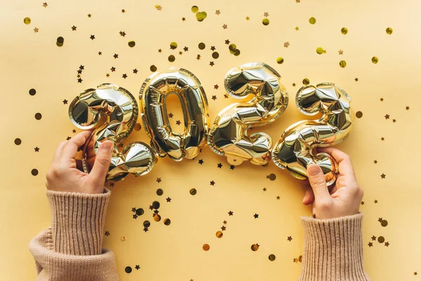 The girl is holding inflatable balloons in the form of New Years figures in 2022. Festive background of the concept of New Year and Christmas. — Stock Photo, Image