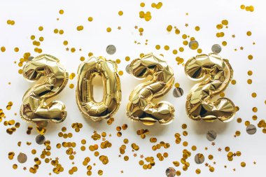 Altın folyodan yapılmış balonlar, üzerinde 2022 rakamları bulunan altın pullu beyaz bir zemin. Noel 'i, yeni yılı ve tatil kavramını kutluyoruz..