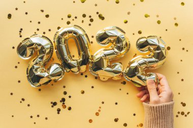 Kız, 2022 'de şişme balonları yeni yıl figürleri şeklinde tutuyor. Yılbaşı ve Noel konseptinin şenlikli arka planı.