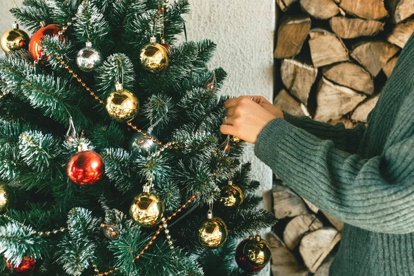 Una mujer decora un árbol de Navidad en casa. — Foto de Stock