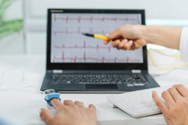 Biyogeribildirim eğitim oturumu. Müşteri parmağına bağlı bir sensör ile kalp atışını izlemek. Kalp atışlarını açıklayan terapist 