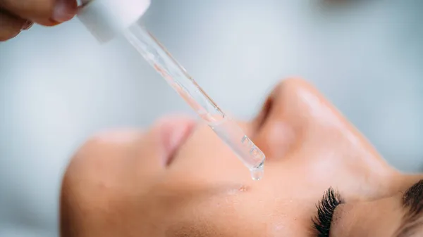 化妆品师应用透明质酸血清治疗妇女脸部 — 图库照片