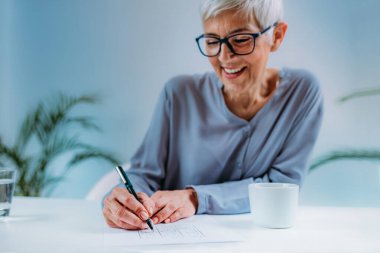 Sudoku bulmacası çözen yaşlı bir kadın. Yaşlılar için bilişsel geliştirme terapisi.