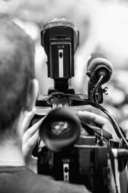 Dışarıdaki bir basın toplantısında çalışan kamera operatörü. Gazeteciler bir medya etkinliğinde resmi giyinmiş siyasetçi veya işadamıyla röportaj yapıyorlar. 