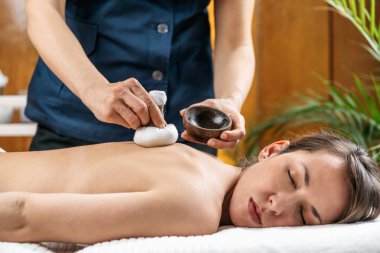 Bitkisel pedlerle Kizhi Ayurveda Masajı. Gözleri kapalı bir kadın sağlık merkezindeki Ayurvedic masaj tedavisinin tadını çıkarıyor..