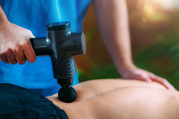 マッサージ銃で腰痛治療 理学療法士マッサージマン下背部 — ストック写真