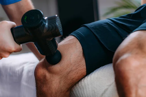 Terapeuta Tratando Músculos Quadríceps Atleta Usando Uma Arma Massagem — Fotografia de Stock