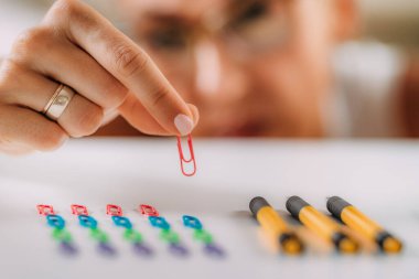 Woman with OCD  Obsessive compulsive disorder concept. Placing paperclips in a straight line.  clipart