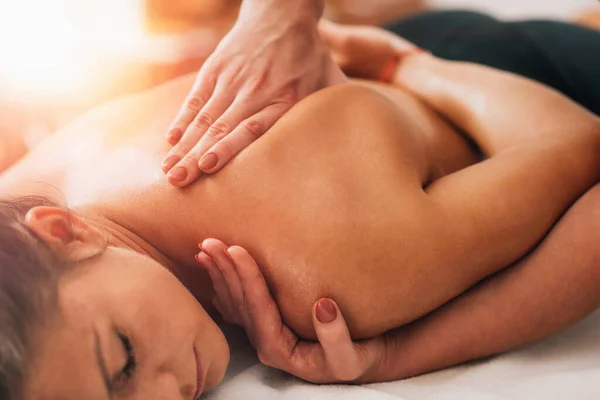 Relaxing neck and shoulder massage. Tanned woman enjoying neck and shoulder massage in a wellness center