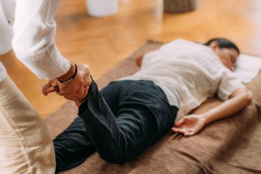 Kadın bacağı geren terapist. Shiatsu masajı 