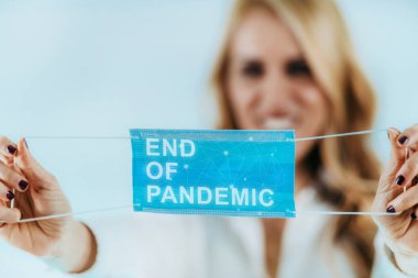 Salgının sonu. Koruyucu maskeyi çıkaran kadın, salgınla ilgili kısıtlamaların sona erdiğini gösteriyor.