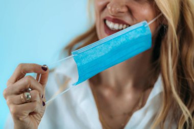 Gülümseyen kadın koruyucu maskesini çıkarıyor..