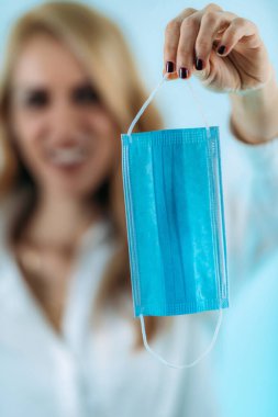 Güzel, gülümseyen bir kadın maskesini suratından çıkarıyor.