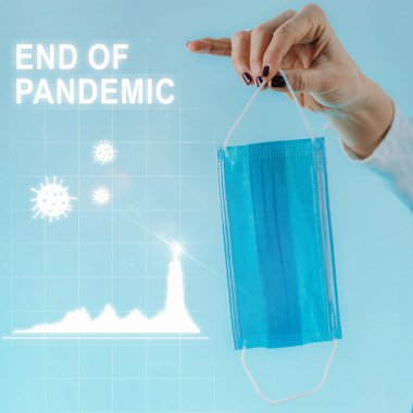 Pandemik kavramsal görüntünün sonu, covid vakalarda azalma, koronavirüs parçacıkları ve buruşuk koruyucu yüz maskesi tutan bir el gösteren bir grafikle. Mavi arkaplan