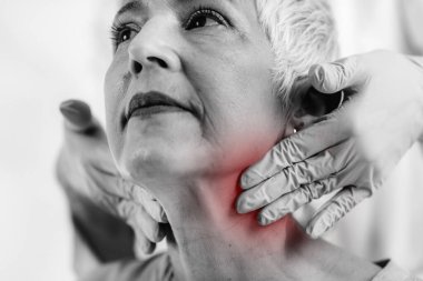 Tiroid bezi kontrolü. Endokrinoloji doktoru klinikteki yaşlı kadını muayene ediyor.. 