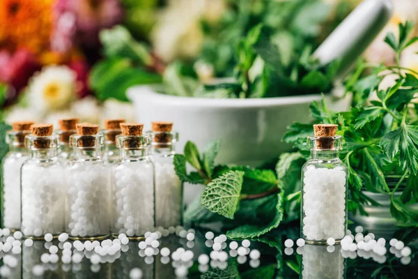 ホメオパシー閉鎖 瓶の中のホメオパシー薬 新鮮な緑のハーブや花で飾られた背景 — ストック写真