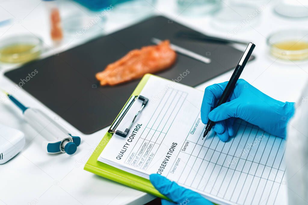 Food Safety and Quality Management. Food safety and quality inspector filling out quality control form in a laboratory, Poultry Sample in background