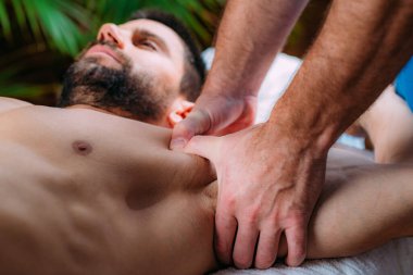 Fizyoterapist, yaralı bir erkek atletin göğsüne masaj yapıyor. Spor sakatlığı tedavisi.