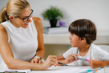 Anaokulu çocuğu okul eğitimi değerlendirme testi yapıyor. Psikolog soru soruyor ve anaokulu çocuğu cevap yazıyor..
