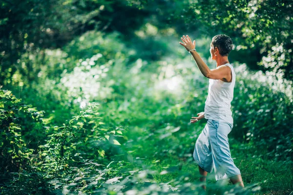 自然とのバランスで 自然の中でエネルギーを与え 受信する心の練習 緑豊かな森の中で瞑想を練習女性 サイドビュー — ストック写真