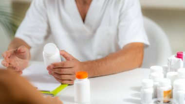 Kuantum Tıbbı. Doctor Holding a Supplement Bottle, bir istemciye ek ürünler öneriyor.