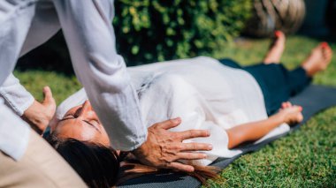 Reiki terapisti barışçıl bir kadının omuzlarında el ele tutuşuyor. Alternatif terapi enerji iyileştirme kavramı.  