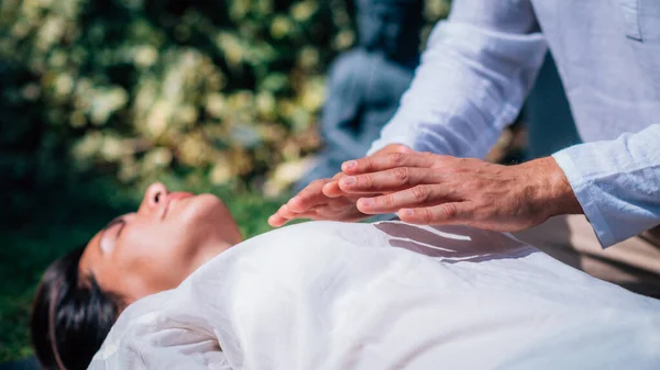 灵气疗程中的女人灵气治疗师手牵手在心脏脉轮之上 传递能量 安静的女人闭着眼睛躺在床上 — 图库照片