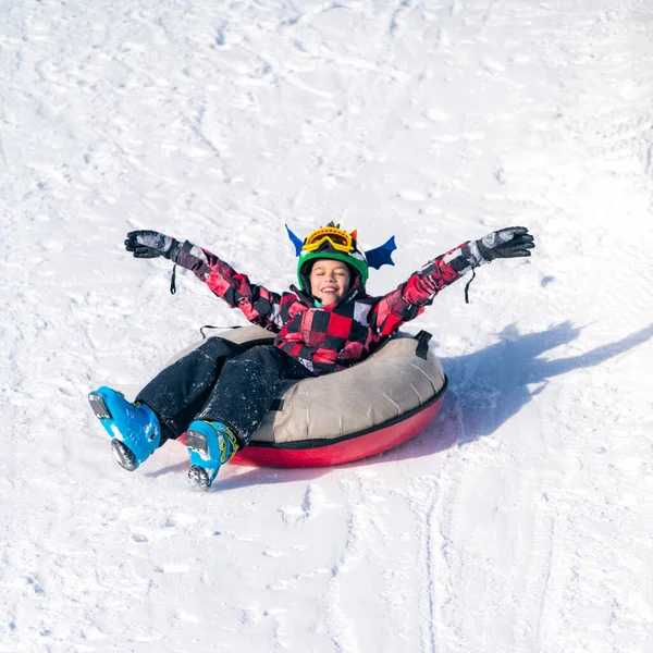 男孩在雪地里滑下小山 — 图库照片