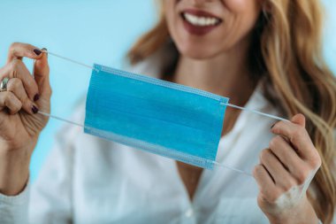 Gülümseyen kadın koruyucu maskesini çıkarıyor..