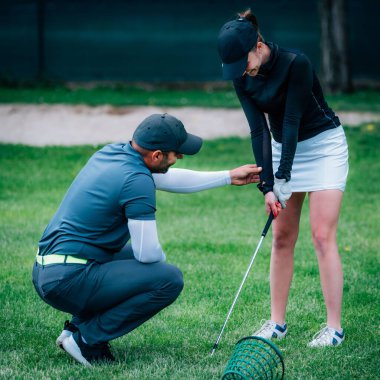 Golf öğreniyorum. Golf hocası ve golf sahasında genç bir kadın.