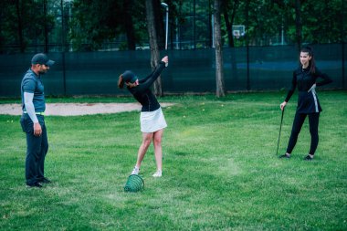 Golf öğreniyorum. Golf hocası ve golf sahasında genç bir kadın.
