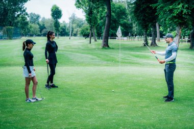 Golf öğreniyorum. Golf hocası ve golf sahasında genç bir kadın.