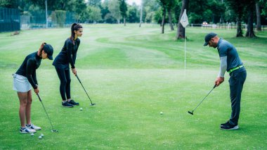 Golf öğreniyorum. Golf hocası ve golf sahasında genç bir kadın.