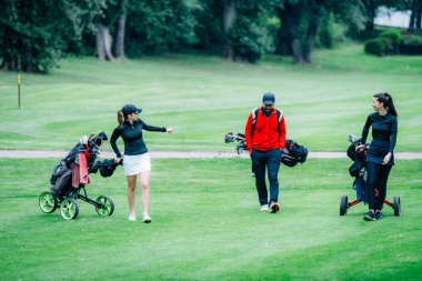 Golf antrenmanı. Golf hocasıyla golf dersi alan iki genç bayan.