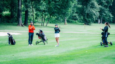 Golf antrenmanı. Golf hocasıyla golf dersi alan iki genç bayan.