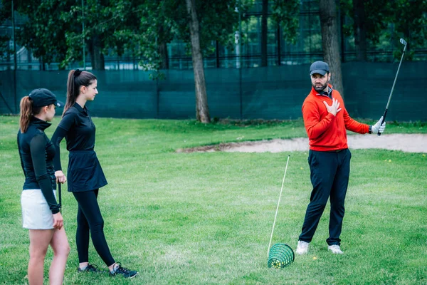 Golf dersi. Golf hocası genç kadınlara salıncak tekniği gösteriyor
