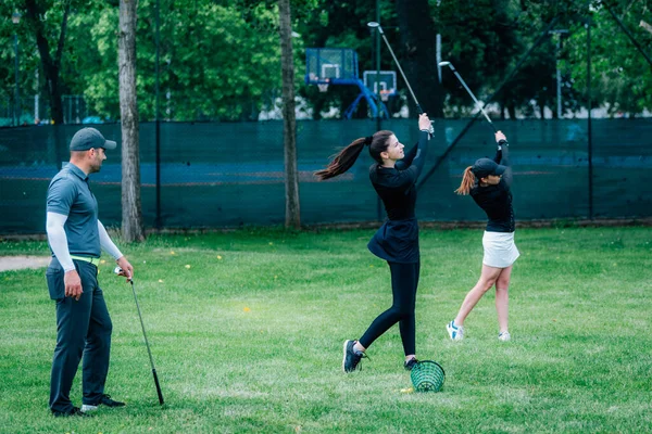高尔夫挥杆技术高尔夫教练与两名年轻女子在高尔夫球场上一起工作 — 图库照片