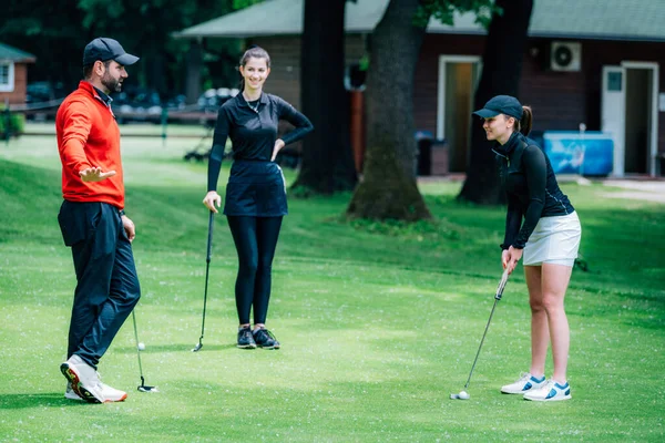 Golf dersi, golf hocasıyla golf antrenmanı yapan iki genç bayan golfçü.