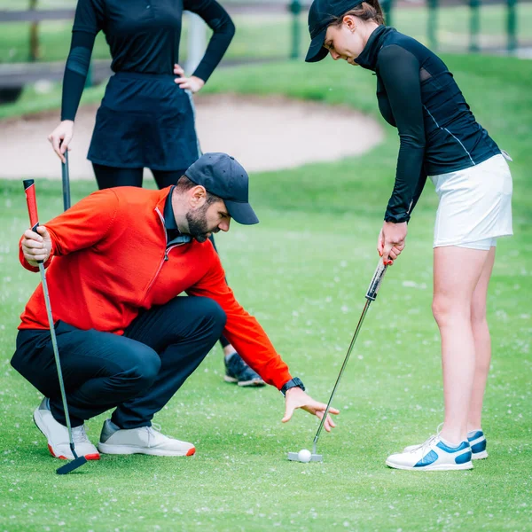 Golf dersi, golf hocasıyla golf antrenmanı yapan iki genç bayan golfçü.