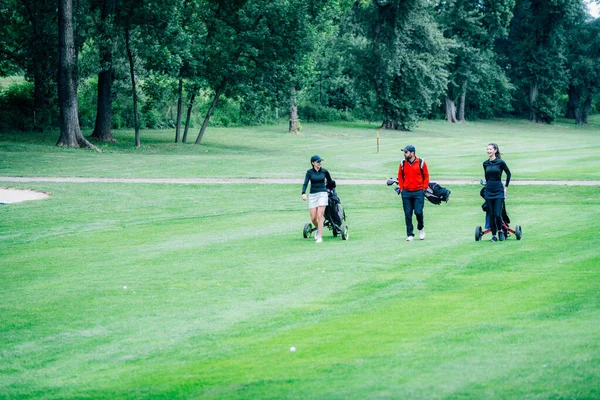 Golf antrenmanı. Golf hocasıyla golf dersi alan iki genç bayan.