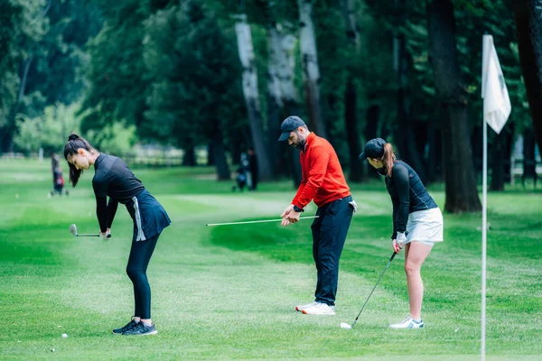 两名年轻的高尔夫球手与高尔夫教练在高尔夫球场练习射击 — 图库照片