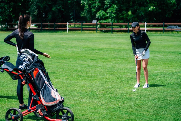 Genç bayan arkadaşlar golf oynuyor.